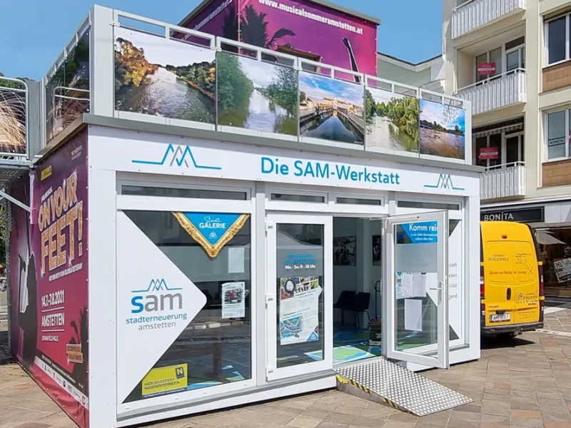 Vita popup-showrooms med foton på taket och skyltar med texten Die SAM-Werkstatt, featuring Glasmoduler, sticker ut längs stadens gator.