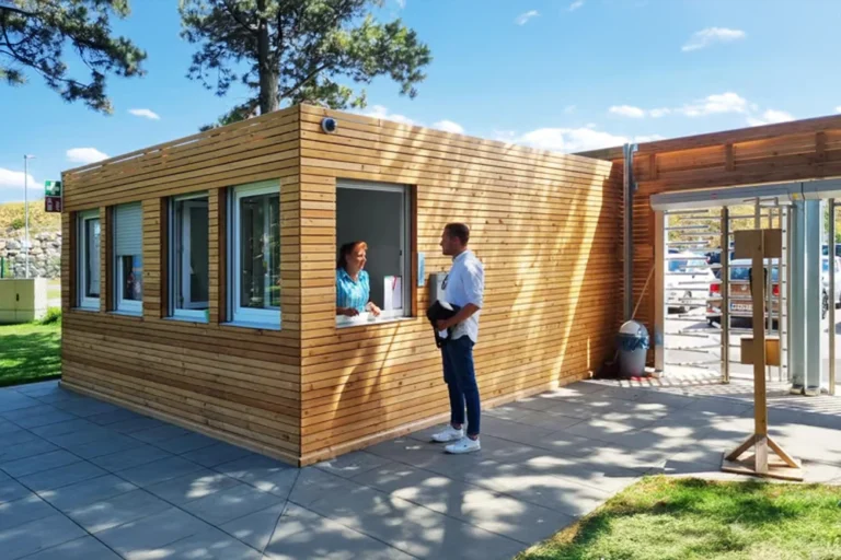 En man står vid fönstret till en butikskiosk i trä och pratar med en kvinna en solig dag.