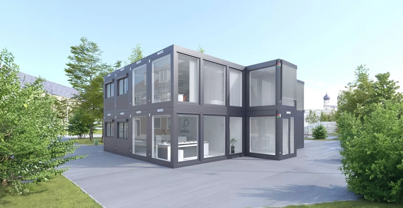 Modern tvåvåningsbyggnad av staplade containrar i glas och metall Kontorsmoduler, omgiven av träd.